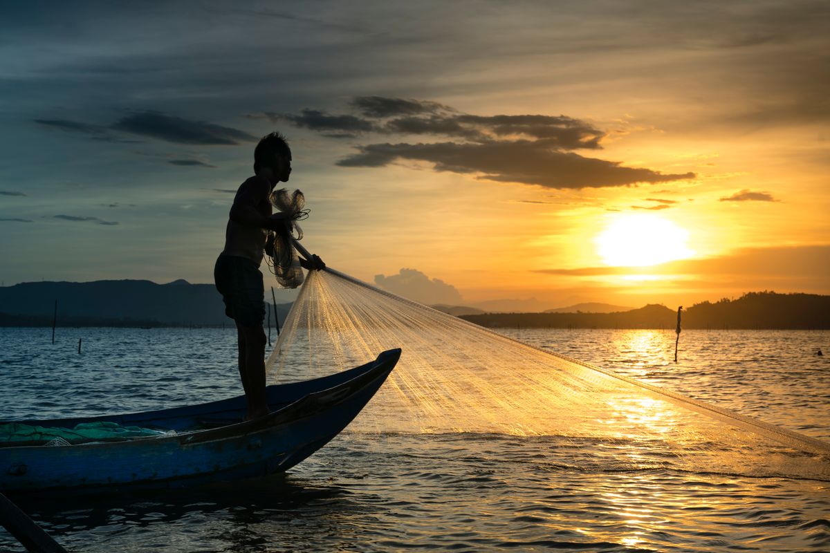 Angler silhouetted against a golden sunset over the water